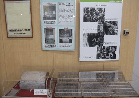 An exhibit featuring display cases and newspaper production