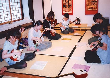 People playing the shamisen in a tatami room