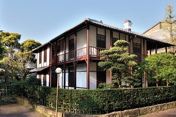 The exterior of a Western-style house seen beyond a hedge