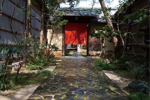 A noren curtain and gate beyond a stone-paved path