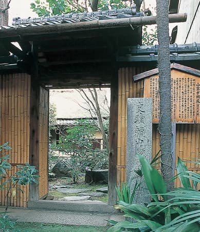 A bamboo fence gate with a stone monument