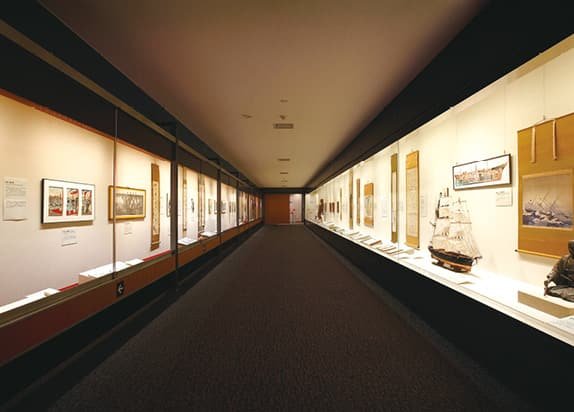 An exhibition passage lined with ship models and related items