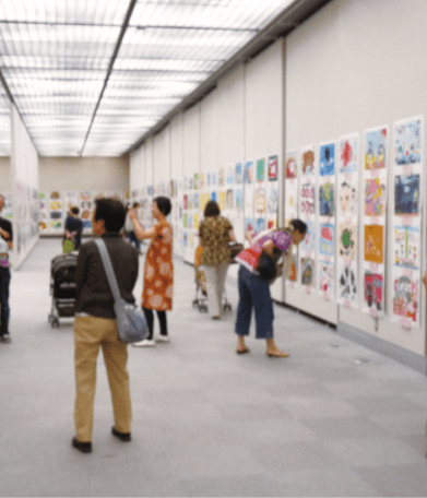 絵が並ぶ展示壁を見る人たち