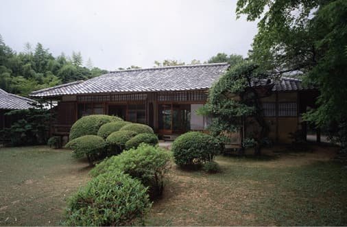 庭木の前に建つ瓦屋根の建物